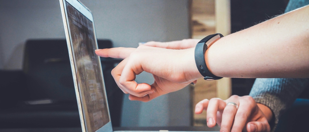 Two people touching a computer